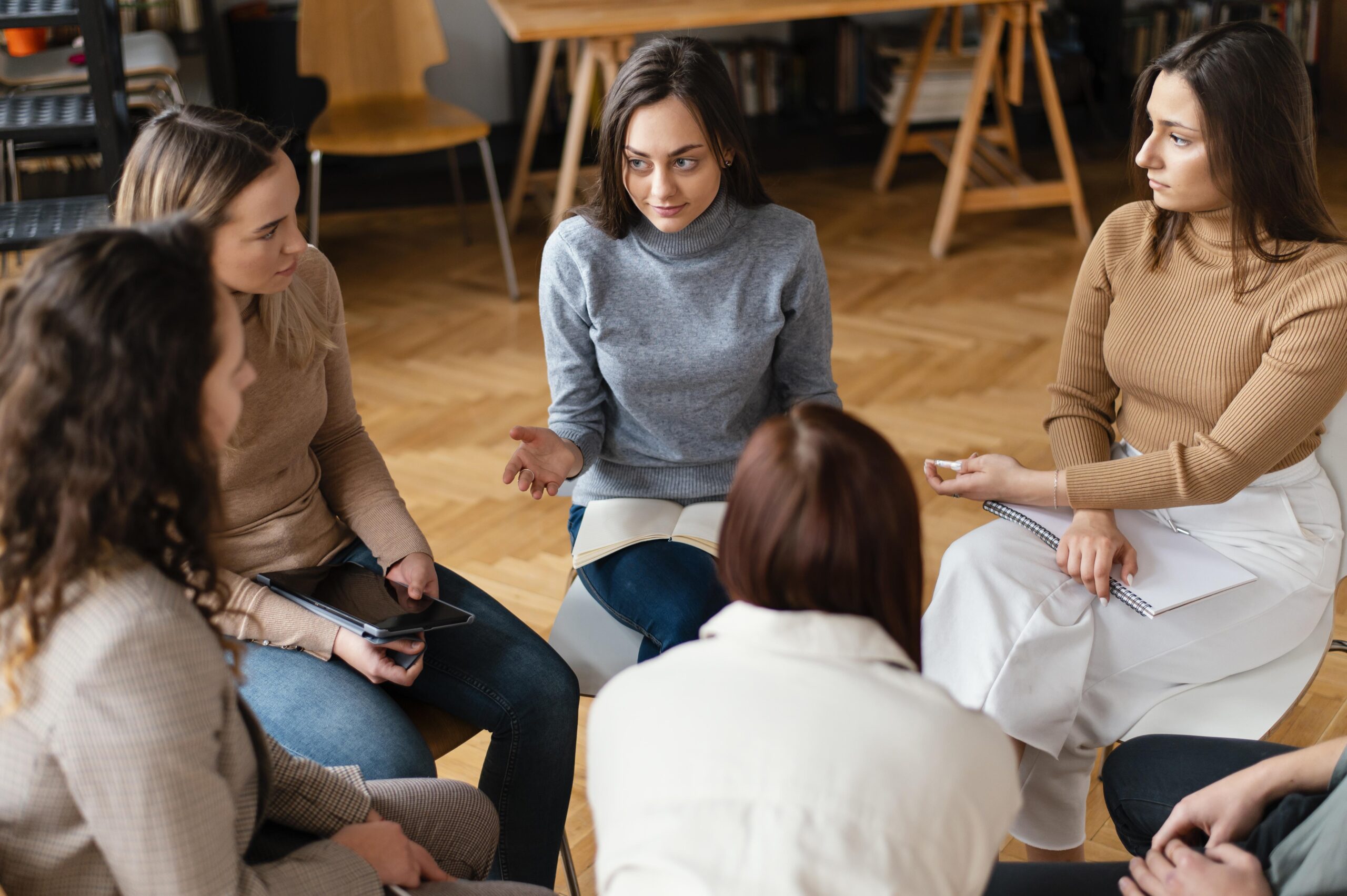 A group of women & men gathered in a community centre discussing initiatives to promote women's safety| safety advice for women